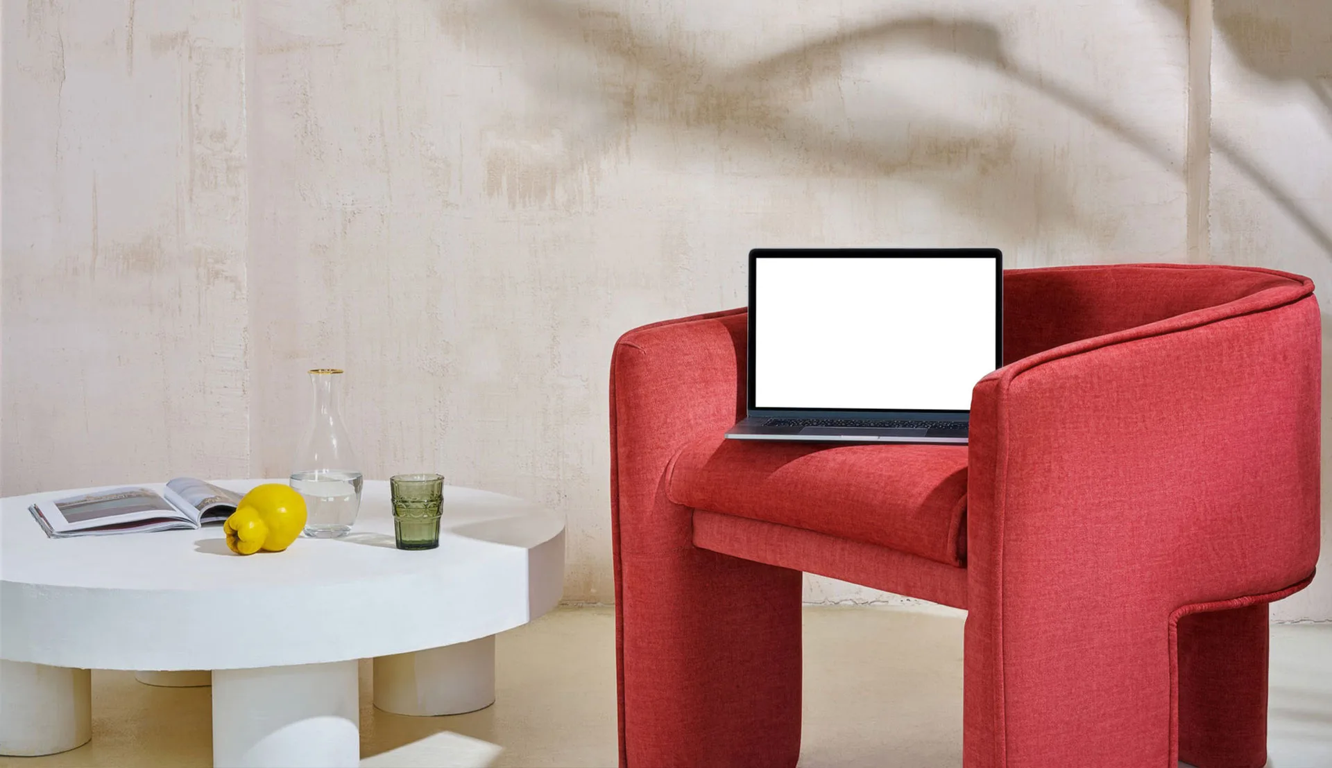 Ein kleiner roter Sessel mit einem Laptop oben drauf und einem kleinen Tisch nebenbei