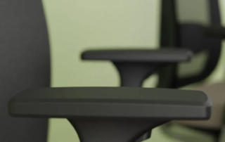 Nahaufnahme der Armlehne eines schwarzen Bürostuhls mit zwei weiteren Stühlen im Hintergrund