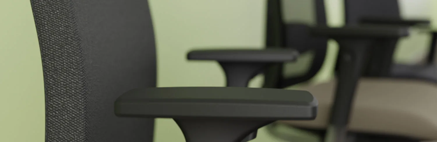 Nahaufnahme der Armlehne eines schwarzen Bürostuhls mit zwei weiteren Stühlen im Hintergrund