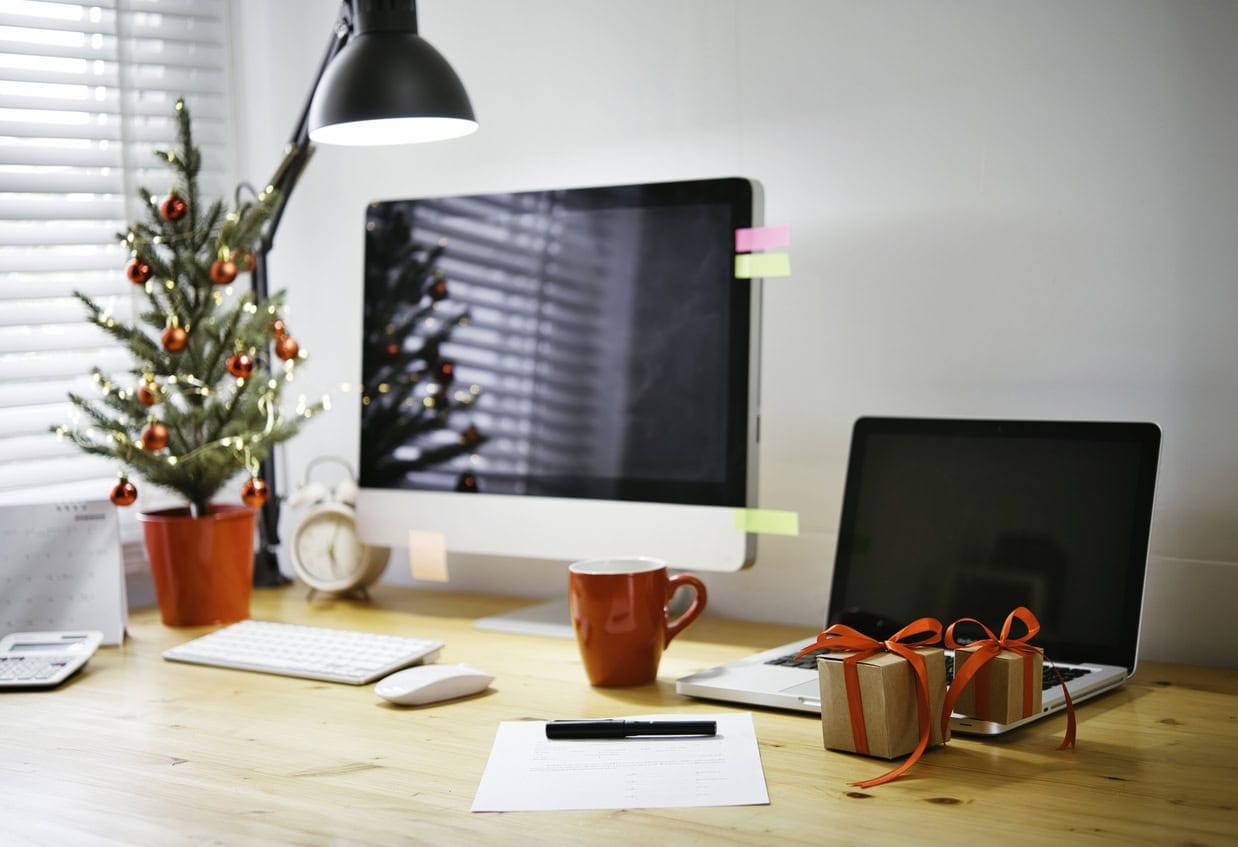 Weihnachtsdeko im Büro – festlich geschmückter Schreibtisch mit Mini-Weihnachtsbaum und Geschenken